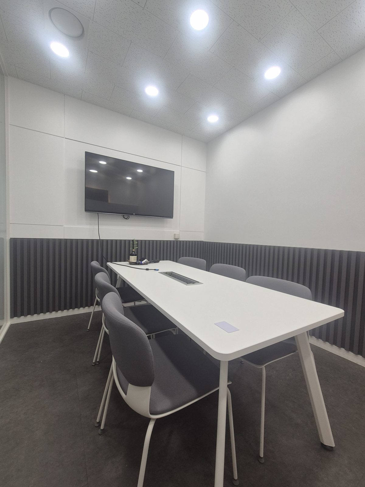 UniHome meeting room with a white table and wall display